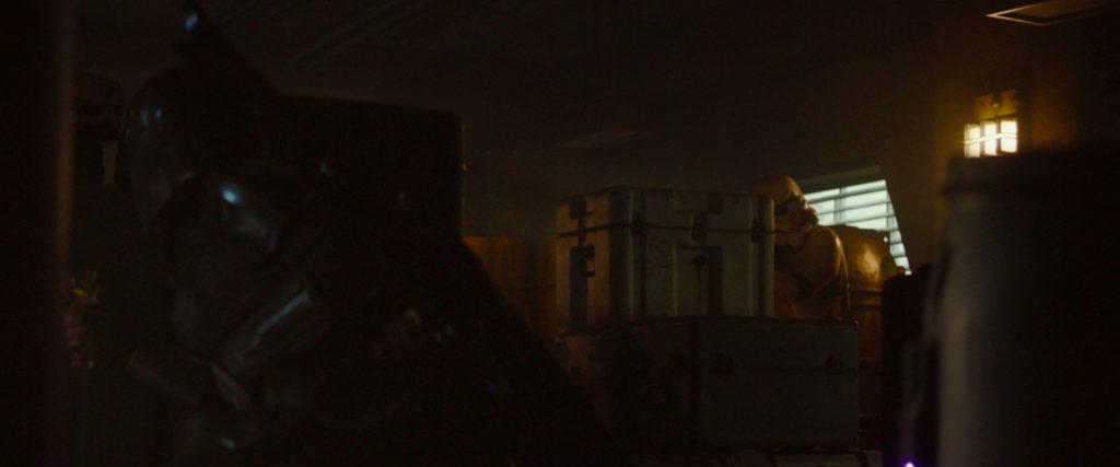The Mandalorian ducks behind containers, capturing Ralph McQuarrie's aesthetic.