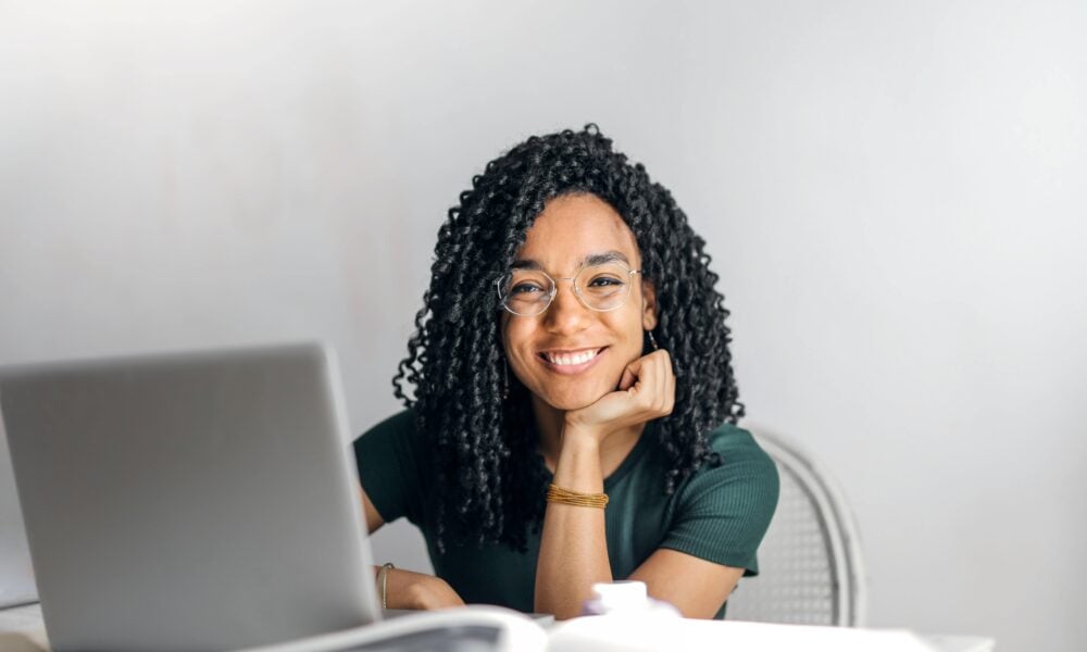 Woman smiling into the camera with laptop on table