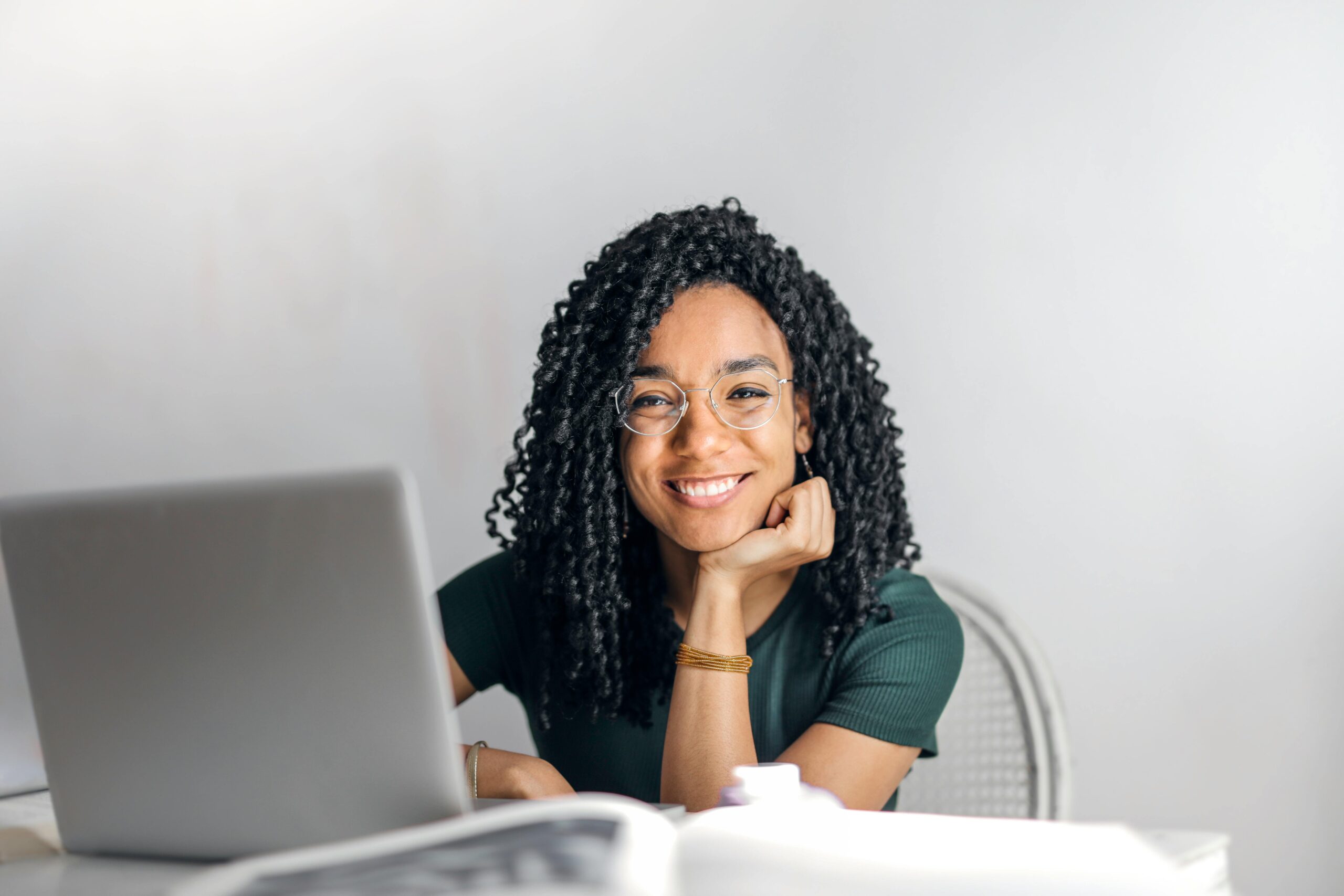 Woman smiling into the camera with laptop on table