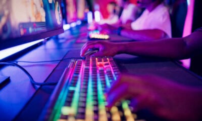 Diverse gamer group players playing competitive MOBA PvP top down view computer game on a stage. Close-up on the hands