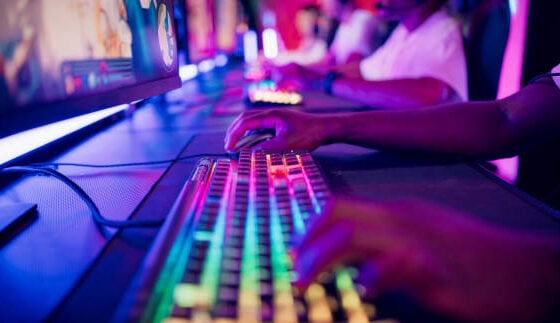 Diverse gamer group players playing competitive MOBA PvP top down view computer game on a stage. Close-up on the hands