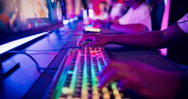 Diverse gamer group players playing competitive MOBA PvP top down view computer game on a stage. Close-up on the hands